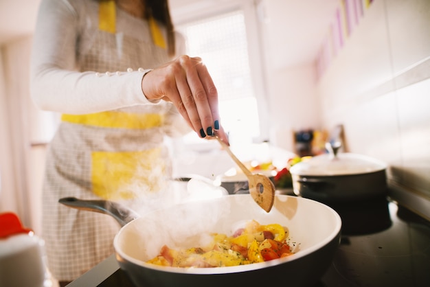 家族のための健康的で栄養価の高い食事は、若い女性によってキッチンで準備されています。