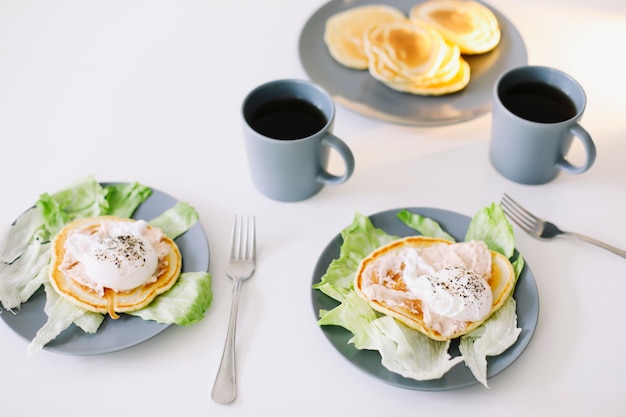 healthy nutritious tasty breakfast with pancakes poached egg on ceramic plate and coffee cup