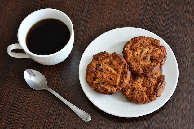 healthy oatmeal cookies isolated on white saucer with cup of black tea, close-up