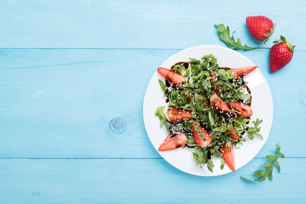 Healthy organic diet salad with arugula, strawberries and sesame with balsamic glaze