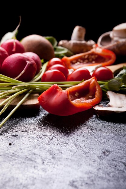 Healthy organic lifestyle concept image with different vegetables on the table. Radish, greengrocery, cutted yellow and red pepper and mushrooms. Copy space available for your text