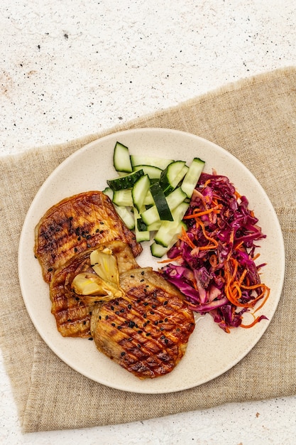 Healthy Paleo food with grilled meat, fresh cucumber, fermented cabbage and carrot