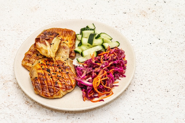 Healthy Paleo food with grilled meat, fresh cucumber, fermented cabbage and carrot