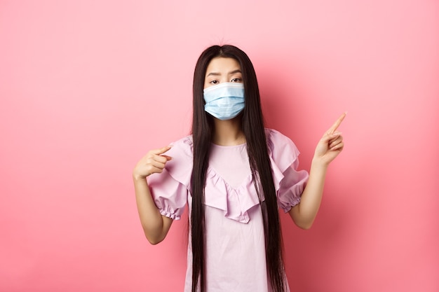 Persone sane e concetto di pandemia covid annoiato donna asiatica in maschera medica che punta a destra mostrando l...