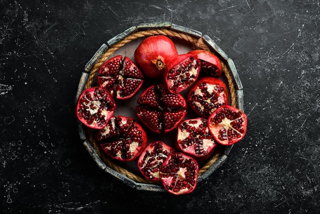 Healthy pomegranate fruit with leaves and open pomegranate in a wooden box Top view