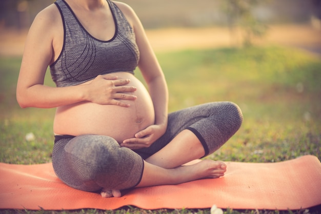 healthy pregnant woman doing yoga in nature outdoor