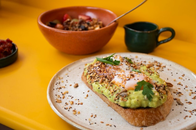 Photo healthy protein breakfast plate with tomato toast with avocado and soft yolk eggs and yogurt with fruit and granola cereal close up