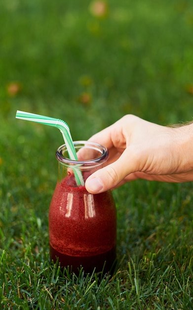 Healthy red detox drink in hand. Fresh beet smoothie jar outdoors.