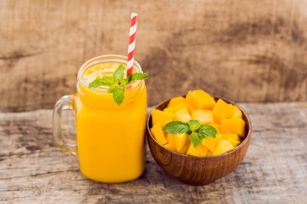 Healthy ripe Yellow Mango Smoothie, Mango fruit and mango cubes on the wooden table, concept healthy food.