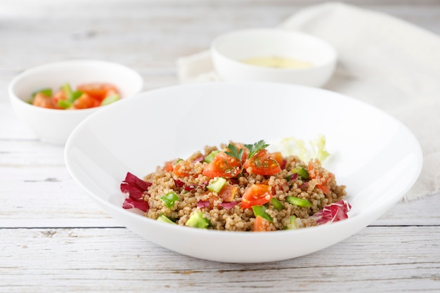 Foto insalata rustica sana della quinoa con le verdure su una tavola di legno bianca