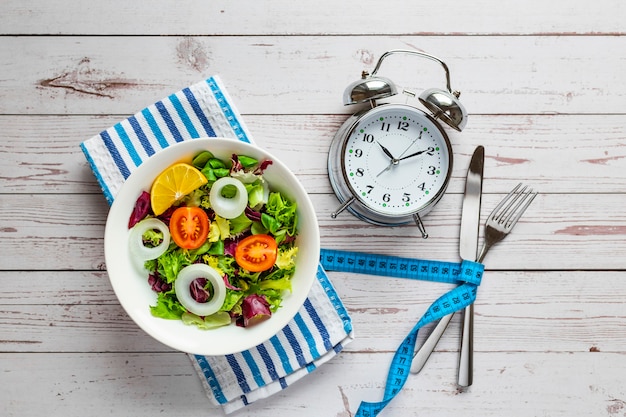 Healthy salad and alarm clock , isolated on wooden background