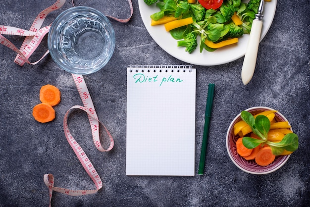 Healthy salad, clean water and measuring tape.  