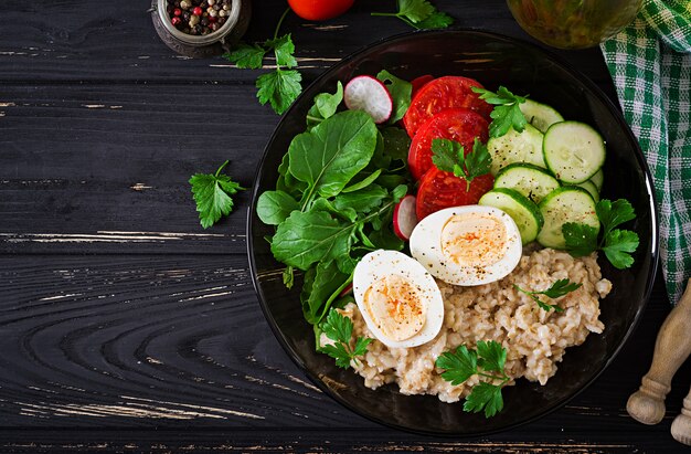 신선한 야채-토마토, 오이, 무, 계란, arugula 및 그릇에 오트밀의 건강 샐러드. 다이어트 음식. 평평하다. 평면도