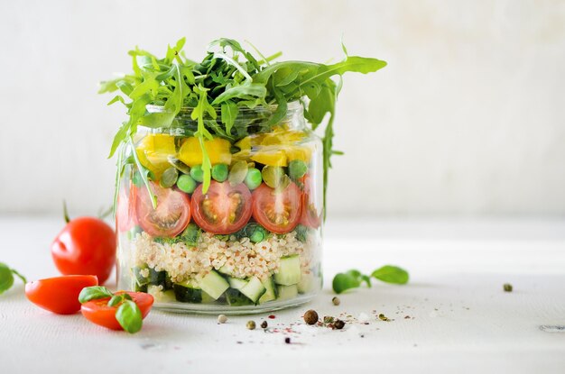 Healthy salad jar with quinoa and vegetables cherry tomatoes cucumber ruccola Raw vegetarian meal for diet detox clean eating Homemade concept