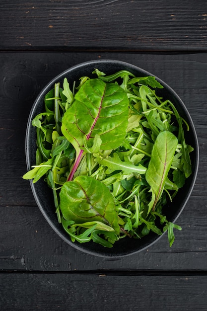 건강 샐러드, 잎 믹스 샐러드 Arugula, Chard 세트, 검은 나무 테이블 배경, 평면도 평면 누워