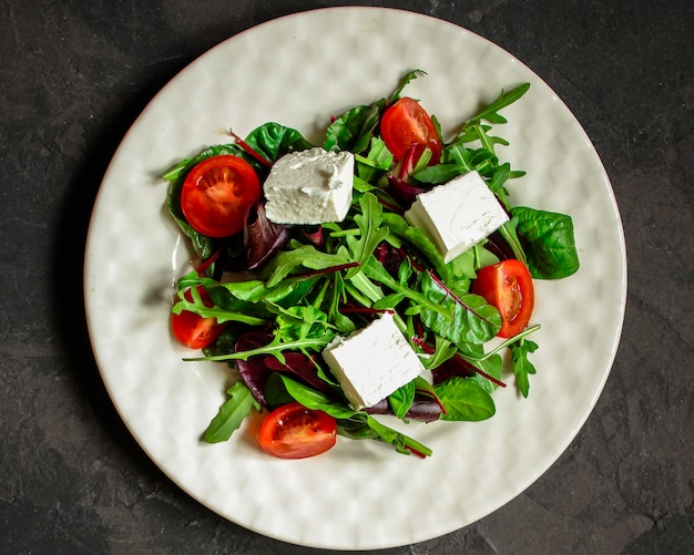 L'insalata sana lascia in un piatto e formaggio bianchi (spuntino succoso). sfondo di cibo