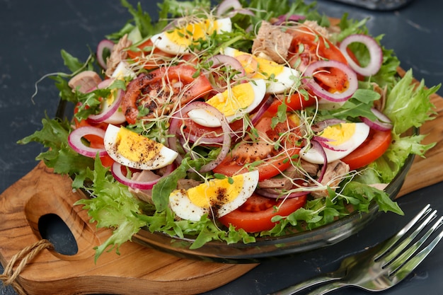 Healthy salad of organic salad with canned tuna, tomatoes, chicken eggs and red onion.