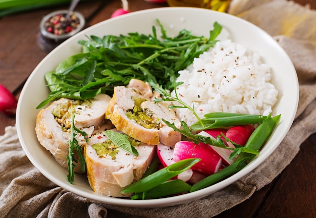 Healthy salad with chicken rolls, radishes, spinach, arugula and rice. 
