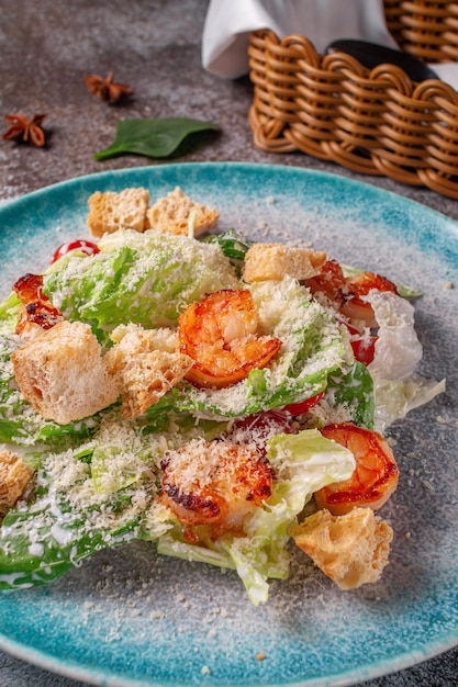 Healthy salad with fried shrimp, greens and croutons in a plate against a gray stone table. A healthy breakfast in a restaurant