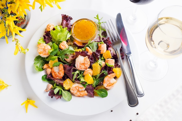 Healthy salad with prawns served on a plate with bowl orange mustard sauce