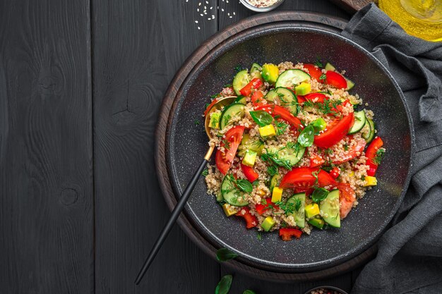 Healthy salad with quinoa vegetables and fresh herbs on a black background Vegetarian salad