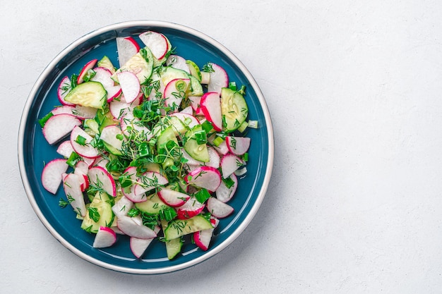 Healthy salad with radish cucumber and micro greens on a light background