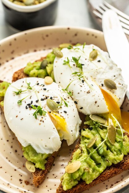 Healthy sandwich with avocado and poached eggs Delicious breakfast or snack on a light background top view