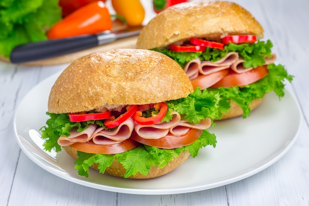 Healthy sandwiches with ham and a wooden board with vegetables