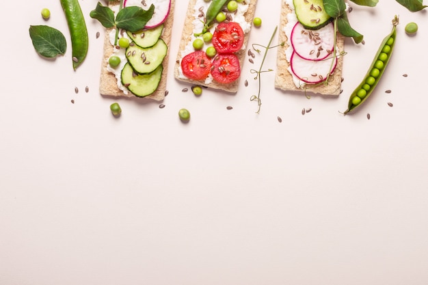 Healthy sandwiches with soft cheese and raw vegetables on crisp bread.