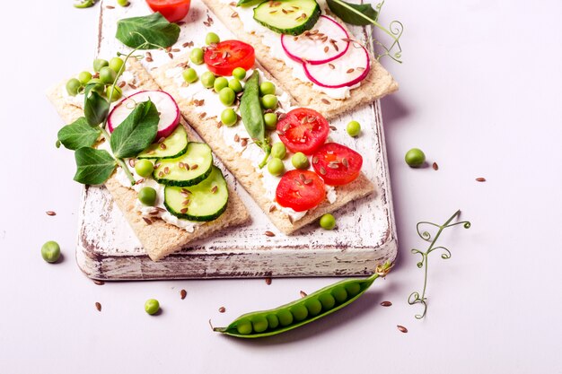 Healthy sandwiches with soft cheese and raw vegetables on crisp bread.