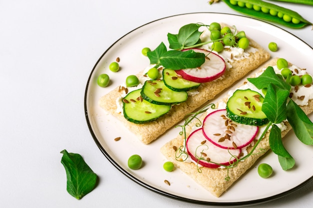 Healthy sandwiches with soft cheese and raw vegetables on crisp bread.