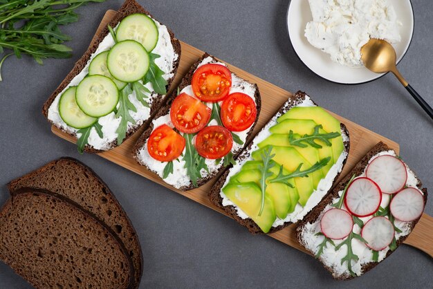 Healthy sandwiches with white cottage cheese cucumber arugula avocado tomato and radish