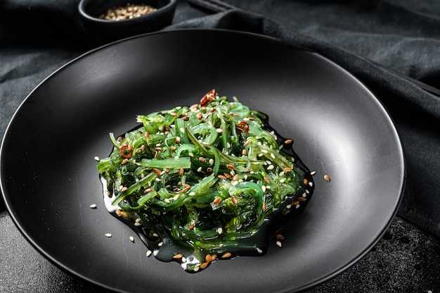 Healthy seaweed chuka salad with greens. Black background. Top view