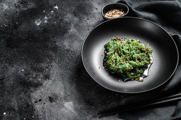 Healthy seaweed chuka salad with greens. Black background