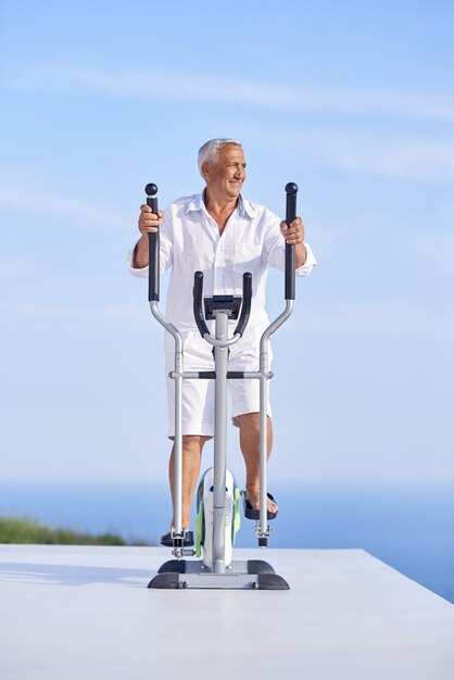 healthy senior man working out on gym treadmill machine at modern home terace with ocean view