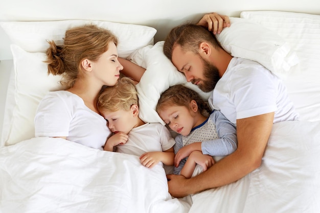 Sonno sano famiglia felice genitori e bambini che dormono nel letto bianco a casa