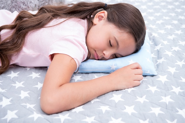 Healthy sleep tips. Girl sleeps on little pillow bedclothes background. Girl child long hair fall asleep pillow close up. Quality of sleep depends on many factors. Choose proper pillow to relax well.