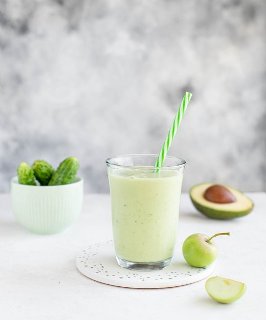 Frullato sano con avocado, cetriolo e mela in un bicchiere con una cannuccia