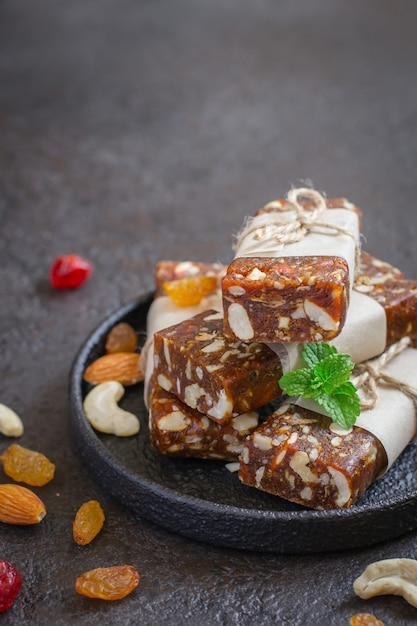 Healthy snack bars of dried fruits and nuts on black concrete background