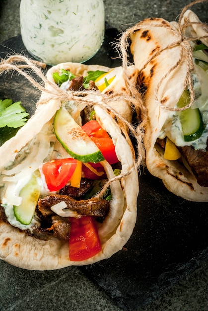 Healthy snack, lunch. Traditional Greek wrapped sandwich gyros - tortillas, bread pita with a filling of vegetables, beef meat and sauce tzatziki