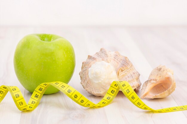 Healthy snack measuring tape on a light wooden surface. preparation for the summer season and the beach, shells, weight loss and sports concept