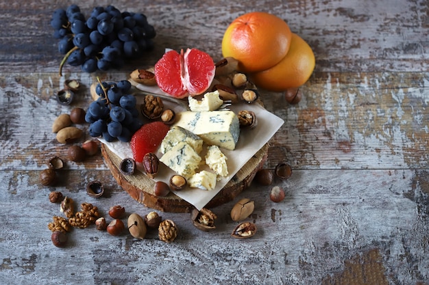 Spuntino sano su un vassoio di legno. formaggio, noci e frutta.