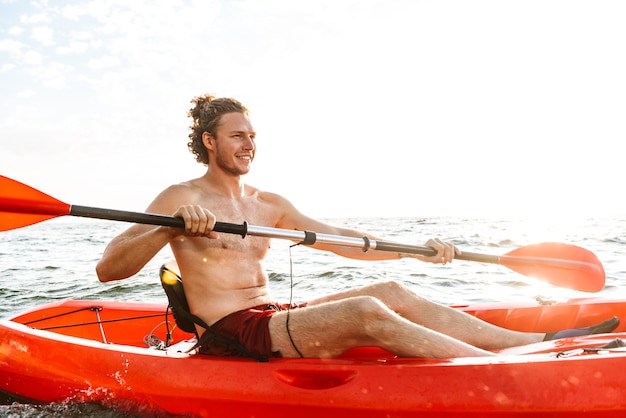 Healthy strong man kayaking on a sea