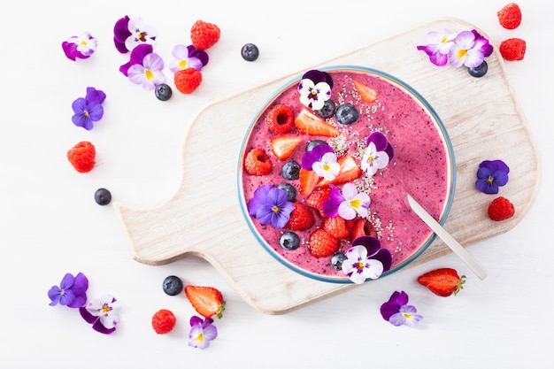 Healthy summer berry smoothie bowl with flowers and chia seed