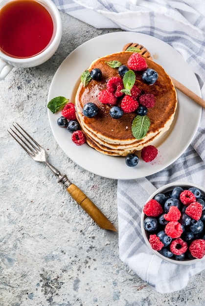 Healthy summer breakfast,homemade classic american pancakes with fresh berry and honey, morning light grey stone surface  above