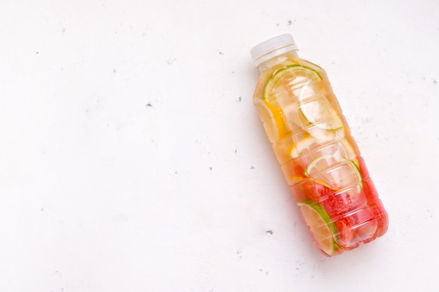 Healthy summer drink with citrus in a bottle on a white background