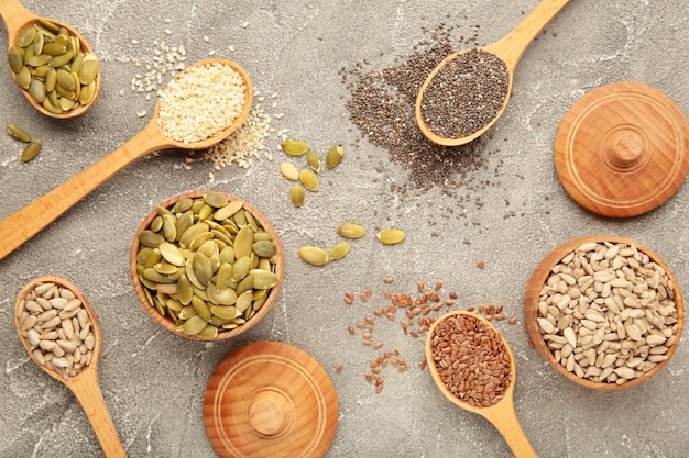 Healthy superfood: sesame, pumpkin seeds, sunflower seeds, flax seeds and chia on grey background. Seeds on spoon