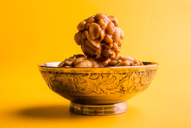 Healthy and sweet groundnut or peanut and jaggery laddoo, served in a brass plate isolated over white background. selective focus