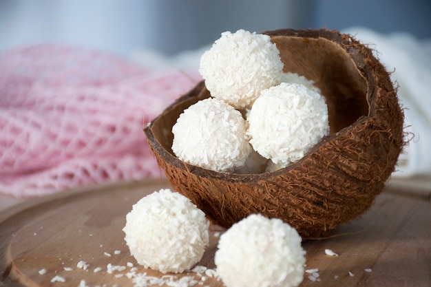 Photo healthy sweets coconut bliss balls in nut shell on wooden board.