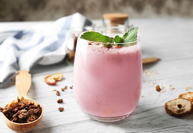 Healthy and tasty breakfast of berry milkshake with dry fruits and mint on wooden table